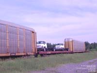 Two GMC trucks go east on a CNA flat car