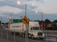 A Purolator tractor is hauling an Arnold Brothers Transport trailer